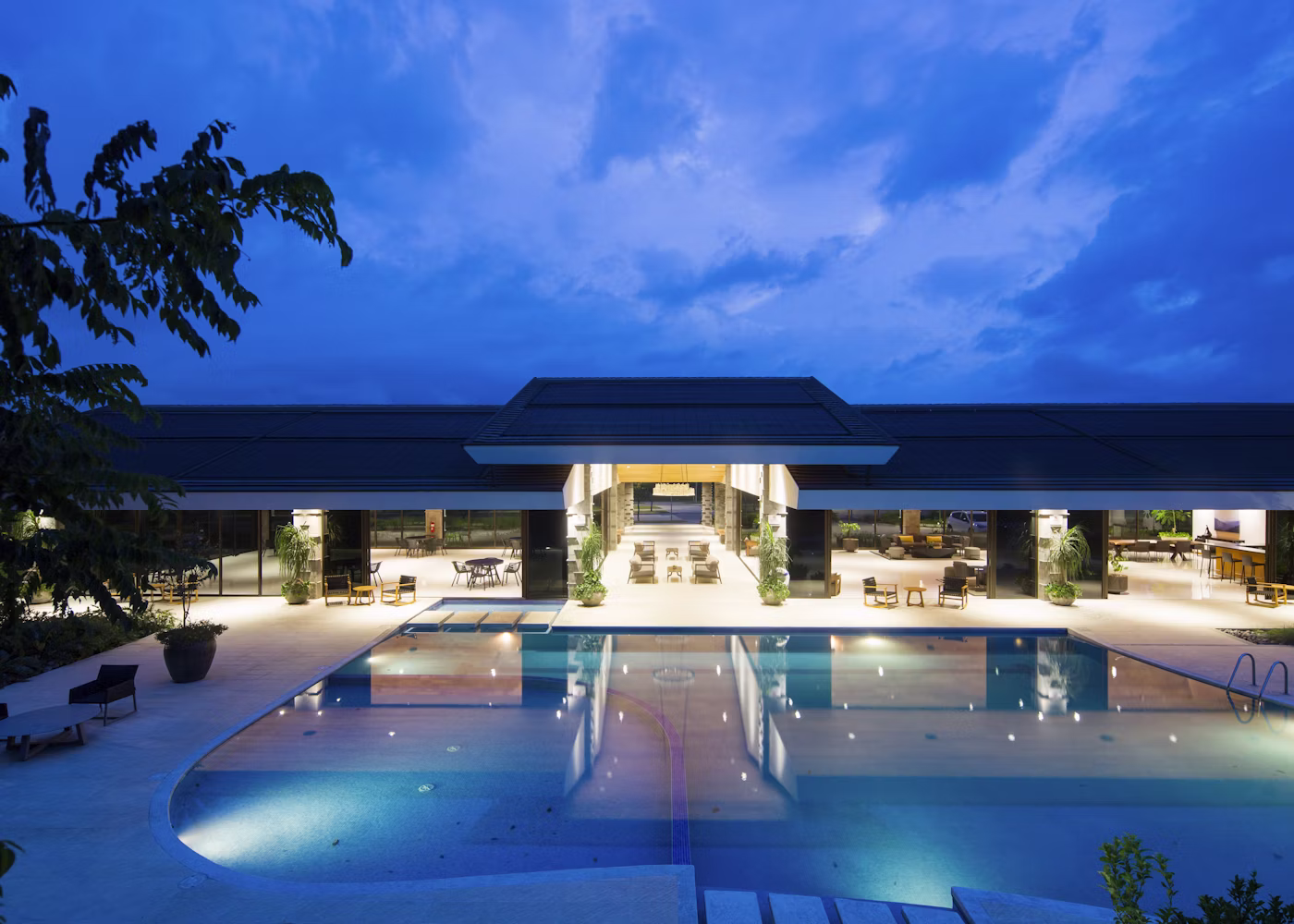 The Velvet Crest Lakeside branch at dusk with a reflective infinity pool