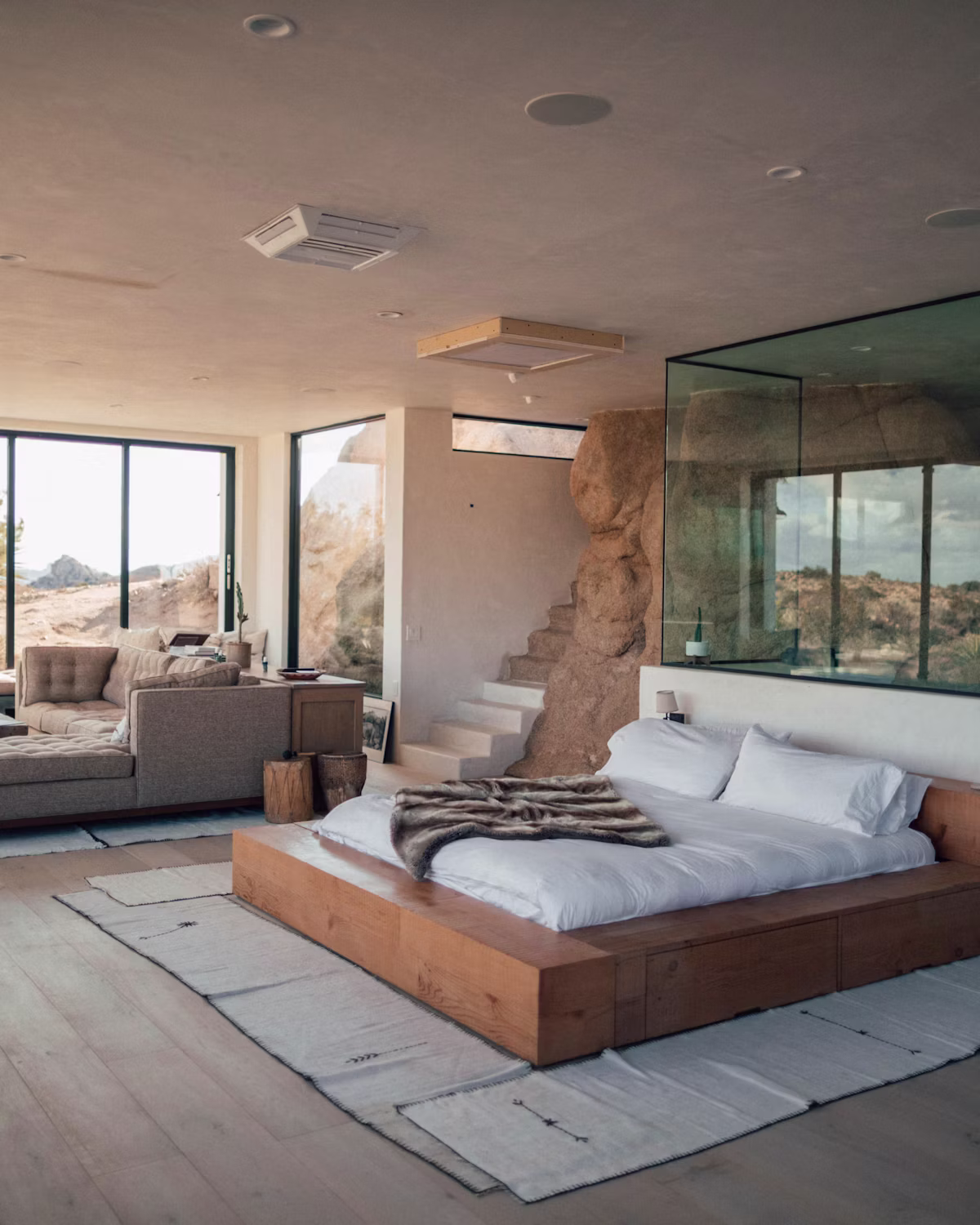 Sunlit corner room with a comfortable bed and floor-to-ceiling windows